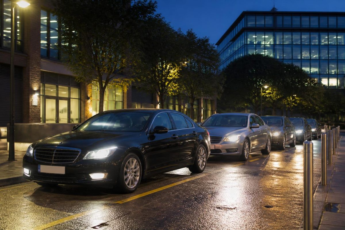 Private hire cars waiting at a city taxi rank at dusk